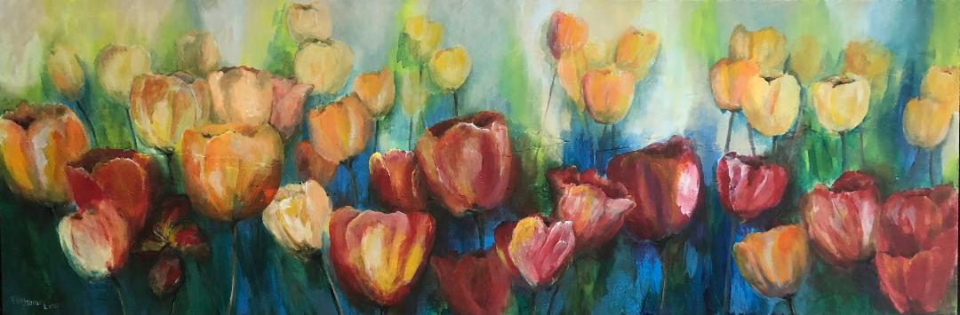 A long panoramic bed of tulips in red, orange and cream against loose green and blue foliage.