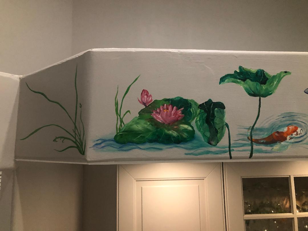 Water lilies, lotus leaves and a single koi painted along a kitchen soffit above the cabinets.