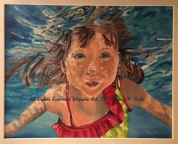 A girl in a red and green swimsuit swimming toward the viewer underwater, hair fanned out and the surface rippling above.